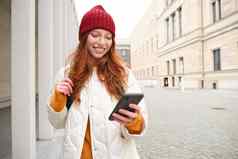 美丽的微笑女孩旅游背包持有智能手机地图移动电话应用程序观光互联网应用程序站在户外