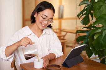 自由远程工人微笑年轻的女人倒咖啡杯坐着咖啡馆数字平板电脑