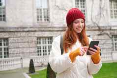 肖像年轻的红色头发的人女人移动电话检查位置智能手机应用程序走城市景点