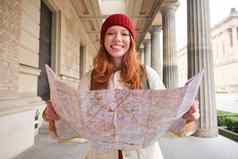 喜欢冒险的红色头发的人女孩走小镇纸地图探讨了城市旅游受欢迎的旅游景点兴奋微笑