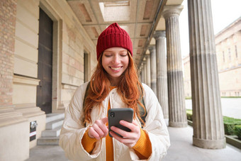 微笑女人红色的头发旅游移动电话应用程序走小镇搜索吸引力访问探索观光智能手机应用程序