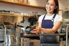 微笑亚洲女孩咖啡师给客户端回来终端支付信贷卡站计数器咖啡商店工作咖啡馆