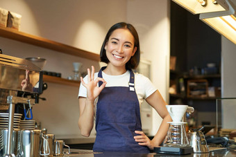 咖啡师计数器显示标志微笑亚洲女孩作品咖啡馆穿蓝色的围裙建议咖啡商店