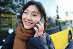 细胞技术人概念时尚的亚洲女孩会谈移动电话使电话调用站公共汽车停止谈话