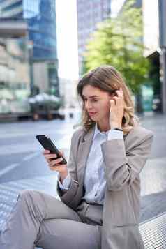 垂直肖像女人西装移动电话阅读消息检查应用程序摆姿势在户外