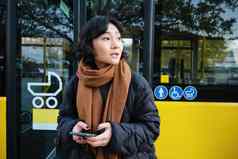 肖像朝鲜文女孩公共汽车停止持有移动电话检查时间表时间表格智能手机应用程序