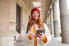 微笑红色头发的人女孩红色的他地图智能手机应用程序检查位置搜索旅馆旅游搜索受欢迎的景点移动电话