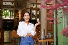 时尚的年轻的亚洲女人站前面咖啡馆入口邀请人女商人老板餐厅自信快乐