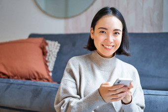 人技术微笑亚洲女人坐着首页移动电话打字消息勃朗宁互联网购物在线智能手机应用程序