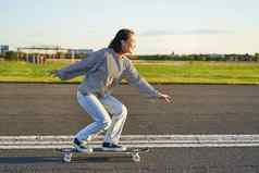 快乐溜冰者女孩骑滑板有趣的空街微笑女人享受巡洋舰骑阳光明媚的路