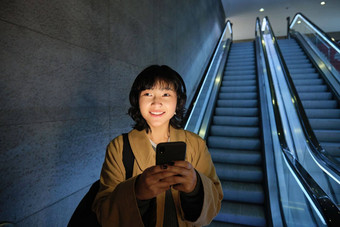 可爱的年轻的女人自动扶梯管地铁地铁上下班工作大学站智能手机