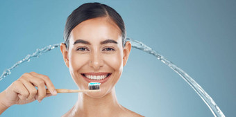 女人刷牙牙齿水飞溅健康牙科清洁口化妆品蓝色的背景淋浴快乐年轻的模型脸肖像牙膏牙刷健康的牙齿微笑
