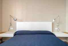 双床上白色床头板覆盖蓝色的床罩一边床边表白色上衣墙灯金属阴影夜间阅读