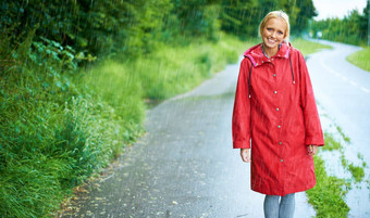 走国家<strong>道路</strong>多雨的一天华丽的年轻的金发女郎女人穿红色的雨衣雨在<strong>户外</strong>国家路
