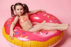 视图迷人的孩子女孩放松浮动甜甜圈游泳环孤立的粉红色的颜色背景