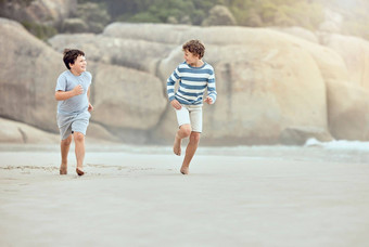 年轻的高加索人男孩运行玩海滩快乐兄弟赛车沙子海岸有趣的夏天假期假期