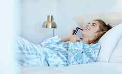 女人电话调用床上早....快乐谈话女智能手机女孩卧室会说话的微笑周末打破沟通无线网络连接放松调用