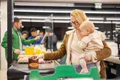 妈妈。购物婴儿婴儿男孩持有孩子叠加产品现金注册超市杂货店商店