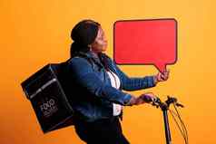 deliverywoman携带外卖热背包骑自行车持有红色的演讲泡沫