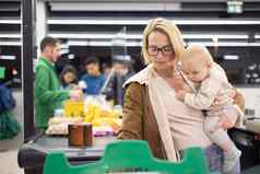 妈妈。购物婴儿婴儿男孩持有孩子叠加产品现金注册超市杂货店商店