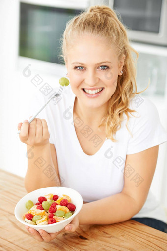 护理水果沙拉有吸引力的年轻的女人吃水果沙拉厨房