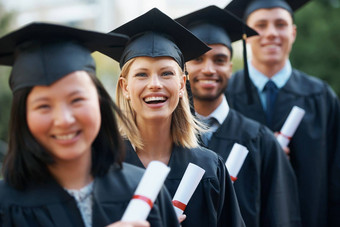 激动毕业生年轻的大学毕业生持有文凭站行微笑