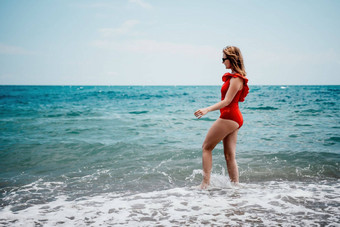 年轻的快乐女人走无忧无虑的<strong>海边</strong>快乐夫人<strong>红色</strong>的比基尼肖像美丽的年轻的女人放松微笑海滩海海洋假期假期旅行旅行