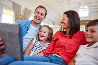 数字娱乐家庭微笑父母坐着年轻的儿子女儿生活房间沙发首页数字平板电脑