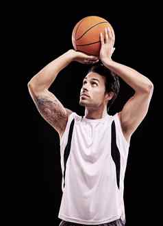 拍摄篮球年轻的男人。扔篮球黑色的背景