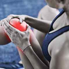 针对疼痛年轻的女人持有受伤的膝盖突出显示红色的