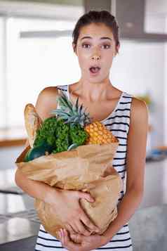 健康的食物使兴奋有吸引力的女人持有袋食品杂货厨房