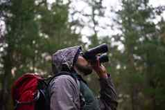 特殊的鸟英俊的男人。双筒望远镜扫描周围森林鸟生活