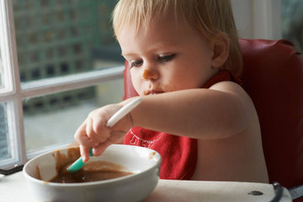 日益增长的男孩食物年轻的婴儿男孩吃心内容高椅子