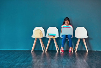 学习在线工作室拍摄年轻的女孩坐着椅子移动PC蓝色的背景