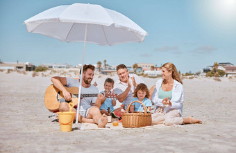 海滩野餐快乐家庭爱吉他音乐成键放松夏天假期假期祖父爸爸妈妈。享受质量时间孩子们兄弟姐妹吃西瓜水果
