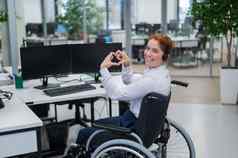 高加索人女人轮椅显示心标志坐着办公室女调用中心工人