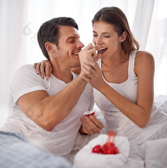 爱男人。喂养巧克力女人床上幸福感情情人节一天浪漫夫妇卧室美味的食物打破浪漫的放松庆祝活动快乐