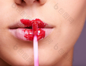 油漆撅嘴特写镜头拍摄女人应用红色的唇彩嘴唇