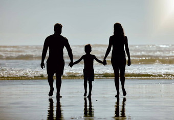 海滩持有手家庭孩子妈妈。父亲轮廓走海洋水天空模型夏天假期假期父母影子支持爱护理孩子海