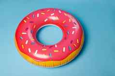 粉红色的充气游泳环甜甜圈救生圈孤立的蓝色的颜色背景夏天假期娱乐概念