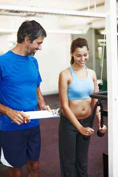 有吸引力的年轻的女人锻炼健身房个人教练需要笔记
