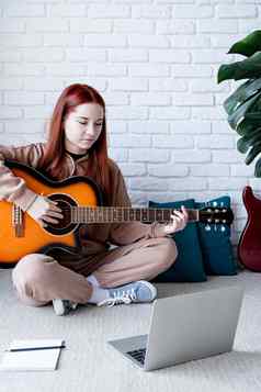年轻的女人学习玩吉他首页