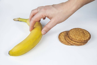 女手使健康的选择采取香蕉饼干健康的吃零食平衡营养饮食生活方式重量损失概念超重男人。选择蔬菜水果拒绝垃圾食物孤立的白色背景