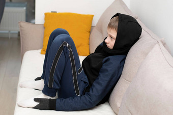 人能源危机概念十几岁的男孩坐在首页沙发上手套罩冻结由于加热转战争欧洲能源危机乌克兰