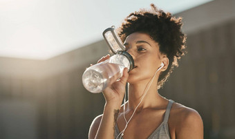 健身喝水黑色的女人听音乐锻炼动机健康健康的生活方式早....城市体育跑步者女孩户外水瓶锻炼音频