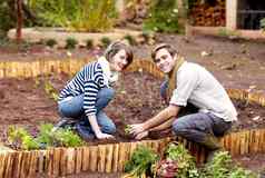 他们狂热的园丁年轻的夫妇种植幼苗蔬菜花园
