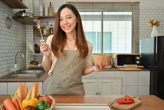 美丽的女人吃健康的沙拉现代厨房室内节食健康的生活方式概念