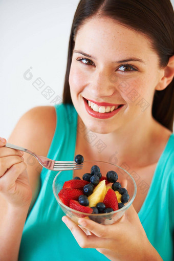 感觉有罪快乐肖像有吸引力的年轻的女人吃水果沙拉微笑