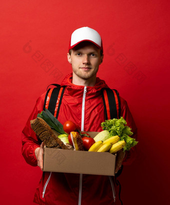 关闭肖像交付男人。红色的统一的交付食物食品杂货蔬菜饮料纸盒子客户端首页在线杂货店购物服务概念