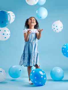 可爱的女孩玩有趣的蓝色的白色气球庆祝活动生日蓝色的工作室背景